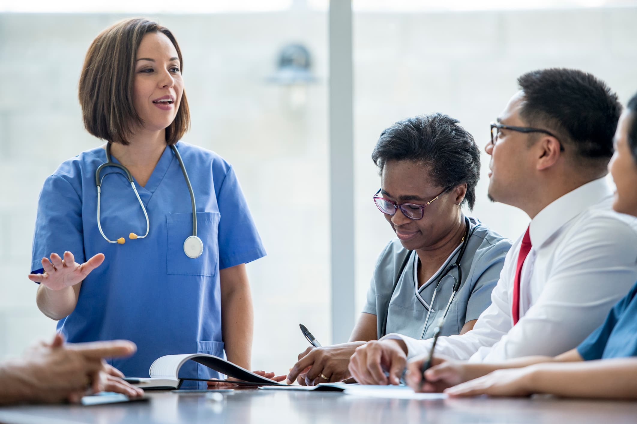 Medical team of physicians reviewing case documents together in a bright hospital meeting room